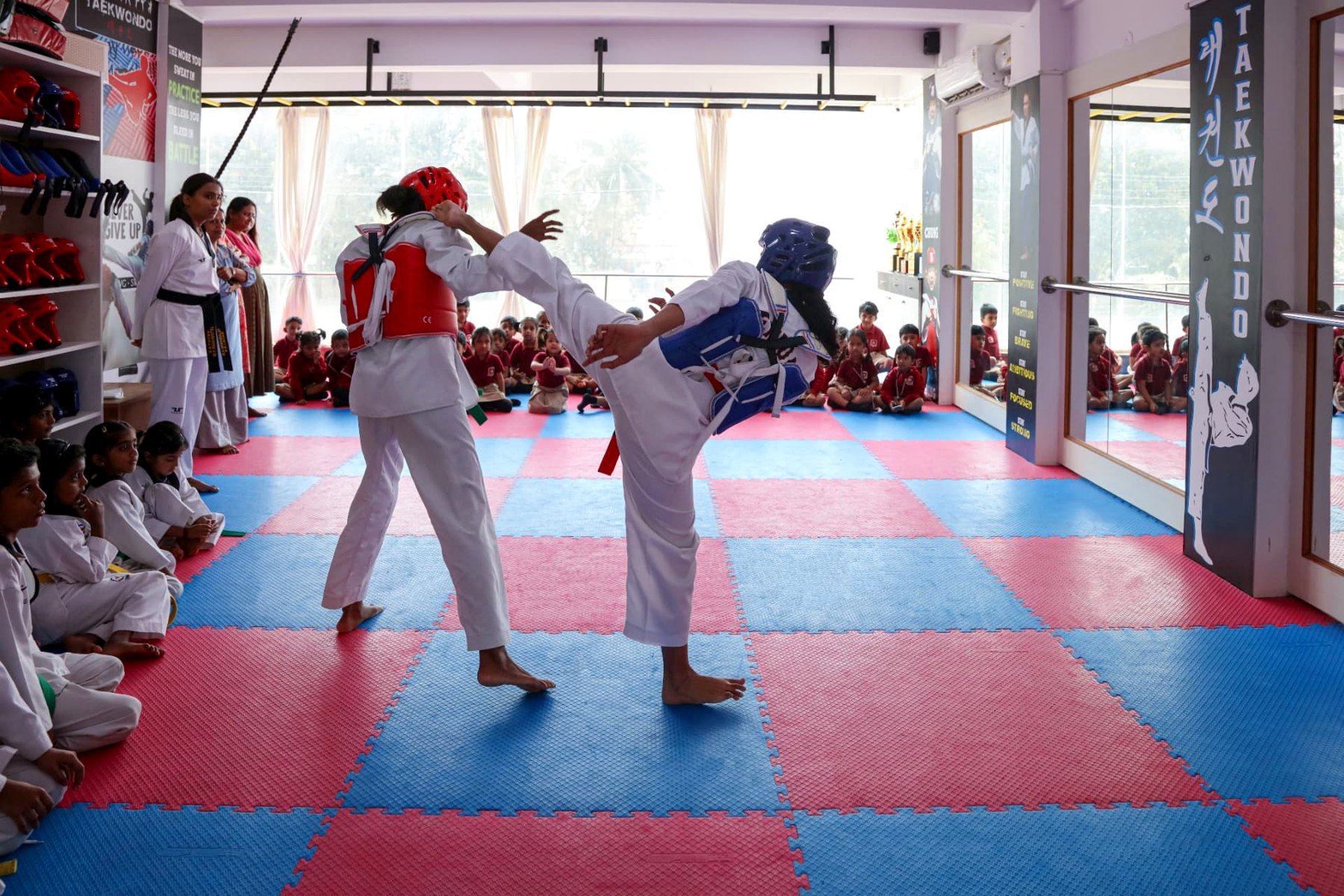 Full-contact sparring in helmets and hoguz in front of the class