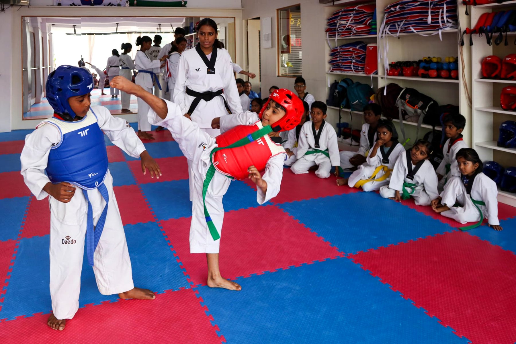 Young warriors sparring with chest guards under the master's watch